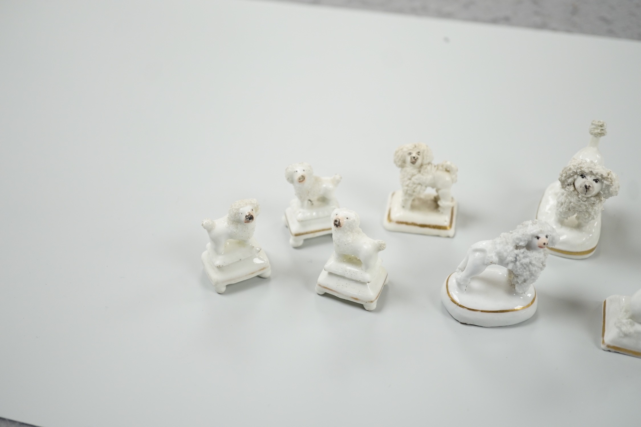 Four small Staffordshire porcelain models of poodles, together with five toy Staffordshire models of poodles, c.1830-50. Largest 5cm tall, Provenance- Dennis G Rice collection